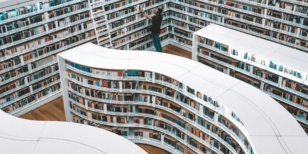 Photo image of a person selecting a book from a series of large, curved bookshelves.
